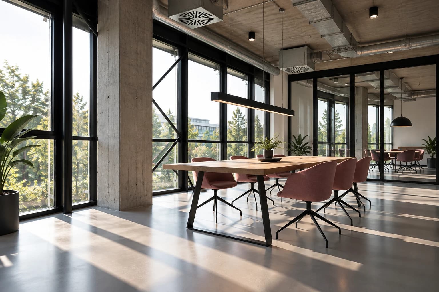 Exposed concrete and steel glazing beside a shared worktable